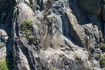 巨岩嶙峋山崖航拍图，绿植点缀粗粝岩面显生机