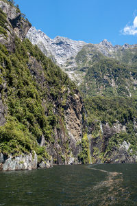 峡湾峭壁瀑布飞泻，绿植覆盖岩壁，碧水映蓝天