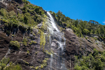山涧瀑布层叠流淌，岩缝青翠繁茂，蓝天为幕