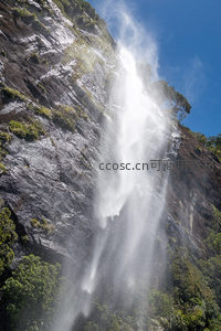 仰角航拍视角下的飞瀑激流，水花四溅映蓝天