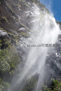 水雾缭绕的悬崖飞瀑特写，岩石肌理与绿意共生