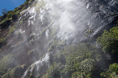 阳光洒落瀑布水幕，晶莹水珠在蓝天下闪耀