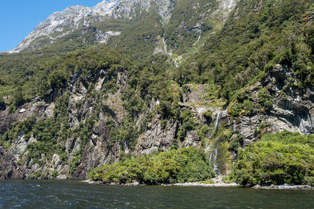 山涧瀑布隐现于葱郁林海间，岩缝渗流汇成清泉注入河谷