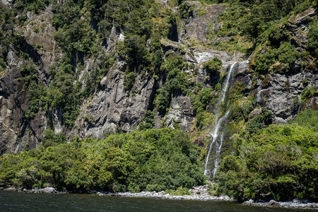 陡峭岩壁间飞流直下的山涧瀑布，绿植覆盖，水光潋滟