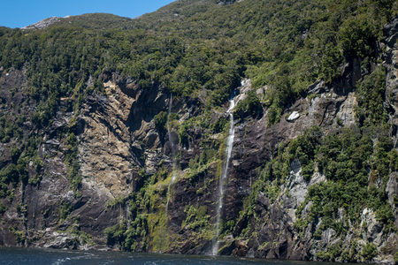 层叠瀑布自岩缝垂落，青翠林木环绕，峡湾静谧如画