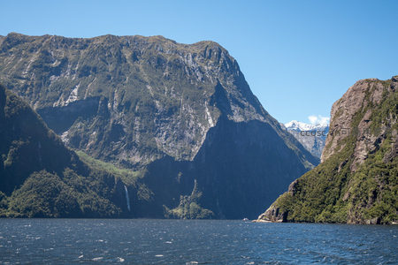 雄伟峡湾两侧峻岭对峙，远峰积雪皑皑，一帘飞瀑隐现林间