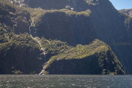 幽深峡谷中瀑布蜿蜒穿行绿茵坡地，水雾轻扬，静谧壮阔