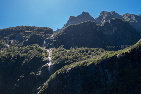 层峦叠嶂间隐现多级瀑布，绿毯覆盖的峡湾地质画卷