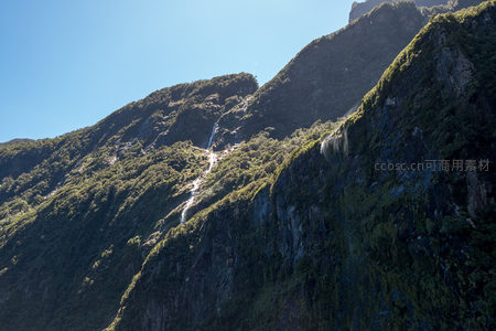 陡峭山脊上多级瀑布蜿蜒而下，林木葱郁光影斑驳