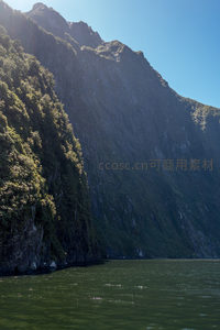 阳光洒落峡湾峭壁，碧水映衬苍翠山崖的壮丽自然景观