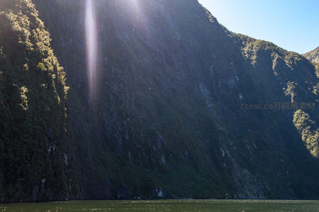 光束直射陡峭崖面，绿植点缀嶙峋石壁，构成史诗级自然画卷