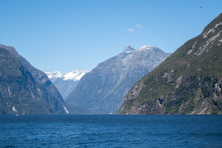峡湾深处雪峰隐现，翠绿山崖与湛蓝天空构成绝美画卷
