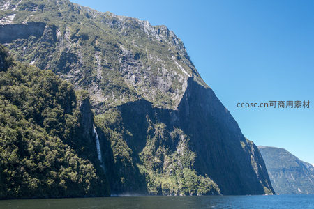 米尔福德峡湾壮丽山崖与飞瀑，碧空如洗映衬翠绿森林