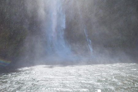 瀑布激流撞击水面掀起浓密水雾，阳光折射出朦胧彩虹，宛如仙境幻境。
