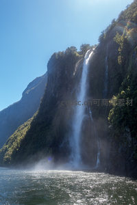 阳光洒落峡湾瀑布群，水帘飞溅生雾，翠绿山崖与湛蓝天空交相辉映