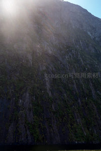 阳光穿透云隙洒落青苔覆岩壁的戏剧性光影