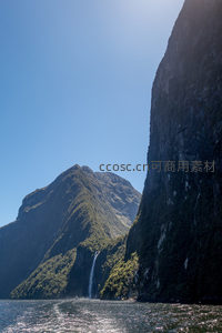 垂直岩壁直插水面，阳光勾勒山脊线条如刀削斧凿