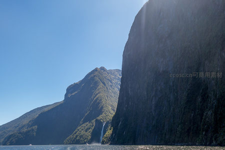 阳光穿透峡湾峭壁，映照层叠绿植与飞瀑奇观