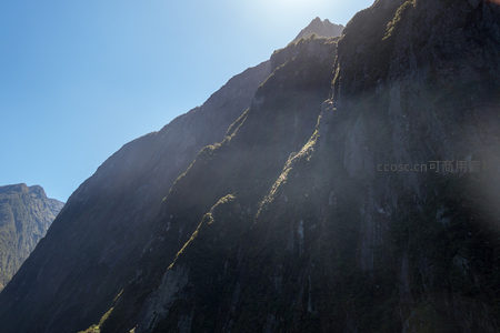 仰望千米高峰：阳光勾勒山脊轮廓，雾气缭绕林线之上