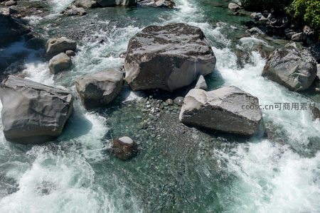 特写视角下激流冲击岩群，水花飞溅显现出清澈河床纹理