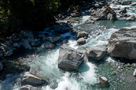 清澈溪流穿行巨石间，水花飞溅显自然力量与宁静之美