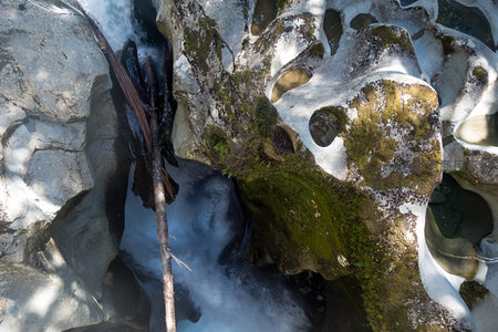 水流蚀刻岩穴，枯枝横卧其间，微观视角呈现地质雕琢奇迹