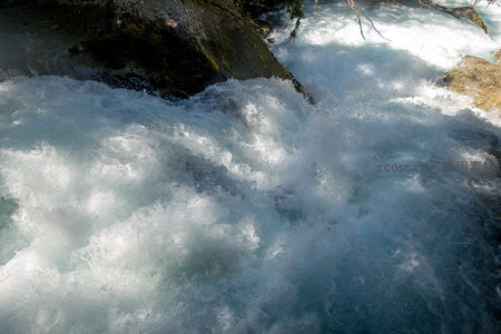 激流撞石溅起千层雪，动态水纹凝固瞬间力量