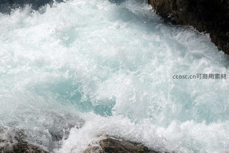 湍急溪流冲击岩石溅起晶莹水花，阳光下泛着蓝白光泽