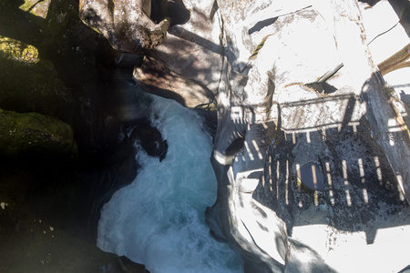 俯瞰峡谷激流穿行岩缝，光影斑驳映照青苔石壁与飞溅白沫