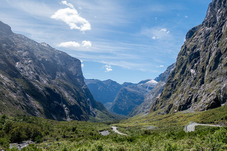 U型峡谷中蜿蜒公路穿行绿谷通向远山雪顶