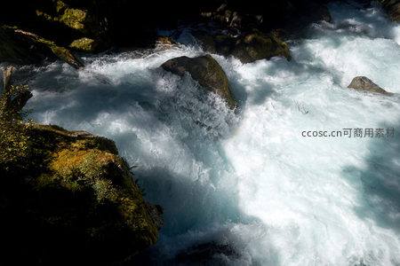 逆光下激流冲刷青苔巨石，明暗对比强烈动感十足