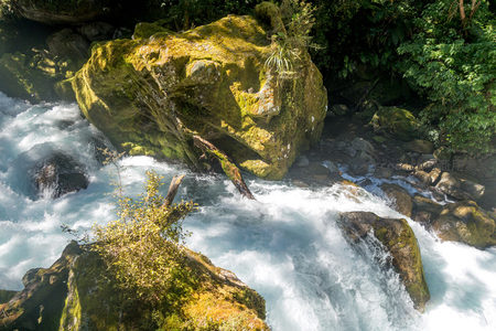 青苔覆盖巨石间湍急溪流奔涌而下，水花飞溅光影交错