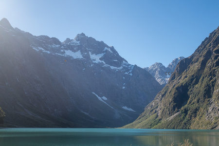 雪山环抱碧蓝湖水，晨光洒落峡谷间壮丽自然风光