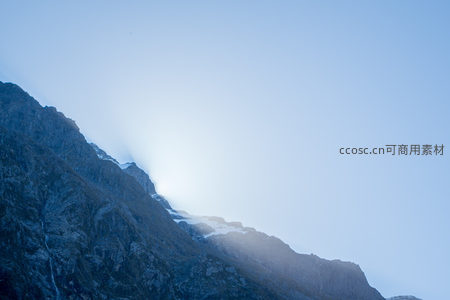 晨曦穿透云雾洒向雪峰山脊，冷色调岩壁勾勒壮丽轮廓