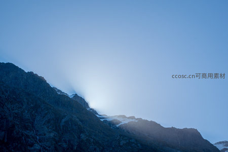 晨曦穿透云隙洒落雪峰，山脊轮廓在冷蓝光中渐显清晰