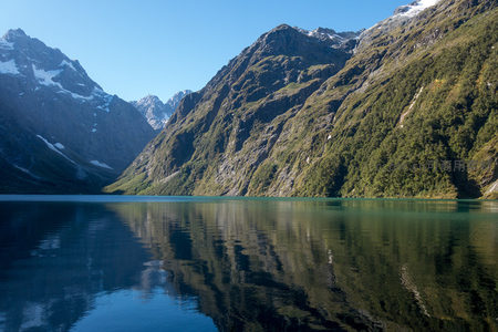 晴空万里下，湖水碧绿通透，山体覆满森林与残雪，生机盎然