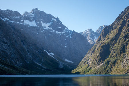 雪山环抱的静谧高山湖泊，倒影如镜映蓝天