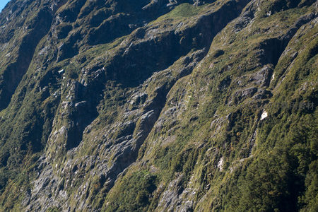 裸露岩壁与苔藓共生的山体特写，航拍呈现地质演化的沧桑质感