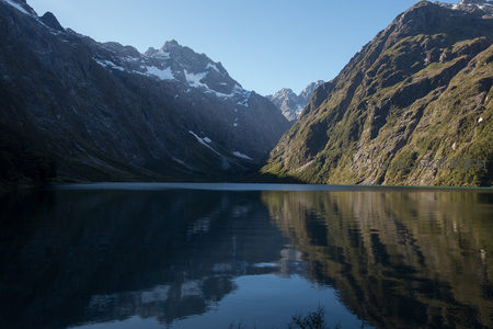 雪山倒影静湖，峡谷绿意盎然，晨光洒落山脊间