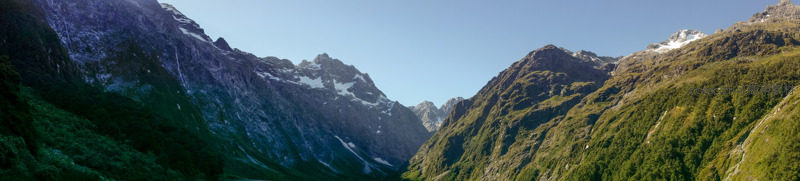 晨曦穿透山谷，雪峰与绿坡交映，湖面如墨镜般倒映天地