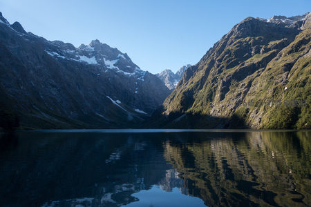 高山湖泊如镜映群峰，雪顶倒影清晰，峡谷幽深静谧，晨光初照