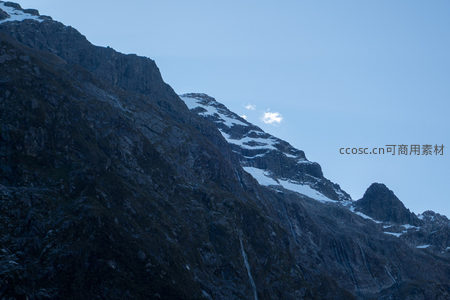 暮色山脊剪影冷峻，残雪勾勒峰线，孤云悬于淡蓝天幕，静谧苍凉