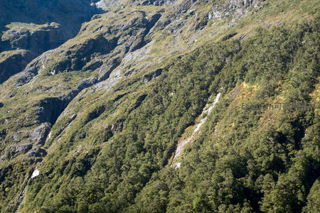阳光穿透云隙照亮山谷林带的航拍生态景观