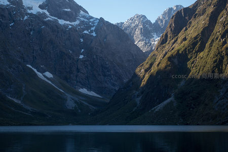 雪山环抱静谧湖面，晨光洒落峡谷深处