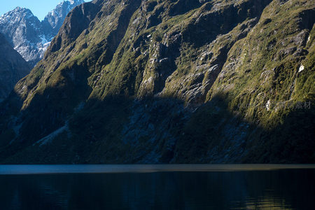 陡峭山崖绿植覆被，湖面倒映深邃岩壁