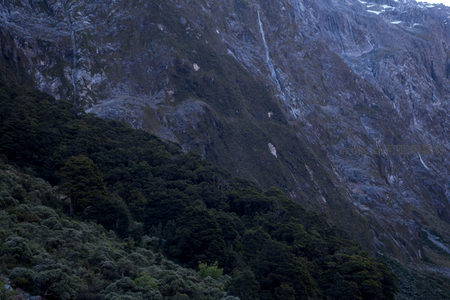 暮色中山峦层叠，林海与裸岩交织成深蓝画卷