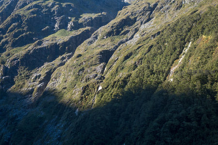 山谷侧翼光影流动，绿植梯田状覆盖岩坡，层次丰富如大地褶皱