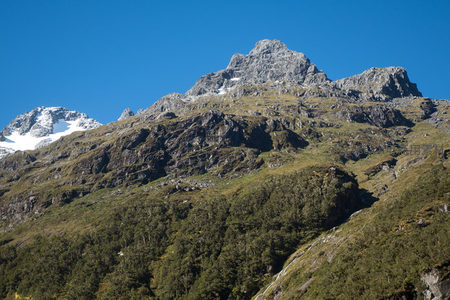 晴空下双峰并立，主峰粗粝岩面与侧峰积雪遥相呼应，气势恢宏