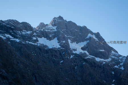 巍峨雪峰耸入云，嶙峋岩壁覆薄雪映晨光