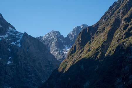 深谷夹峙雪峰隐，光影流转间显山势险峻